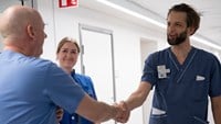 Vårdpersonal och sjukhusdirektören Christophe Pedroletti står och pratar vid en sjukhuskorridor. 