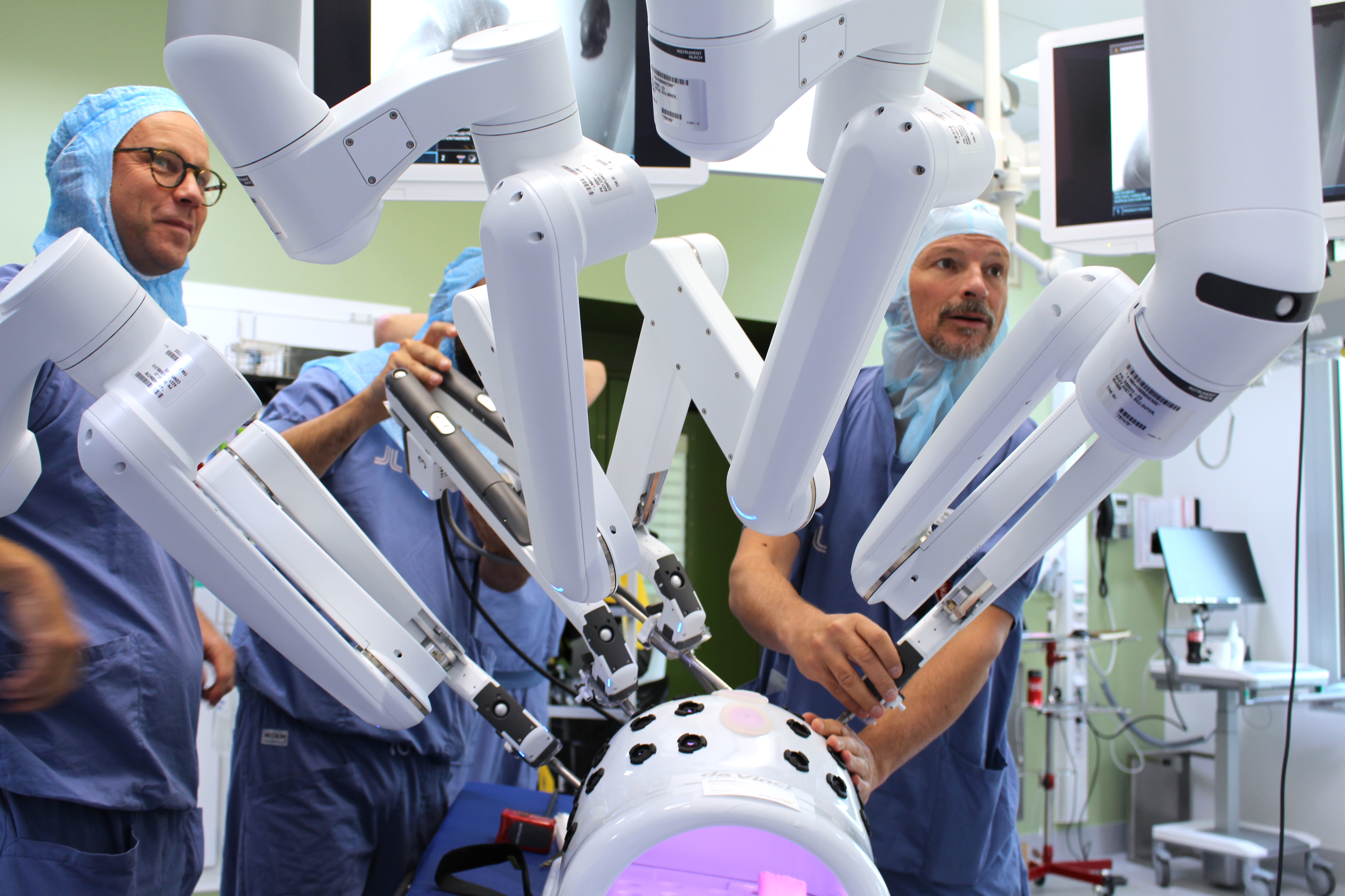 Tre operationsklädda personer förbereder roboten.