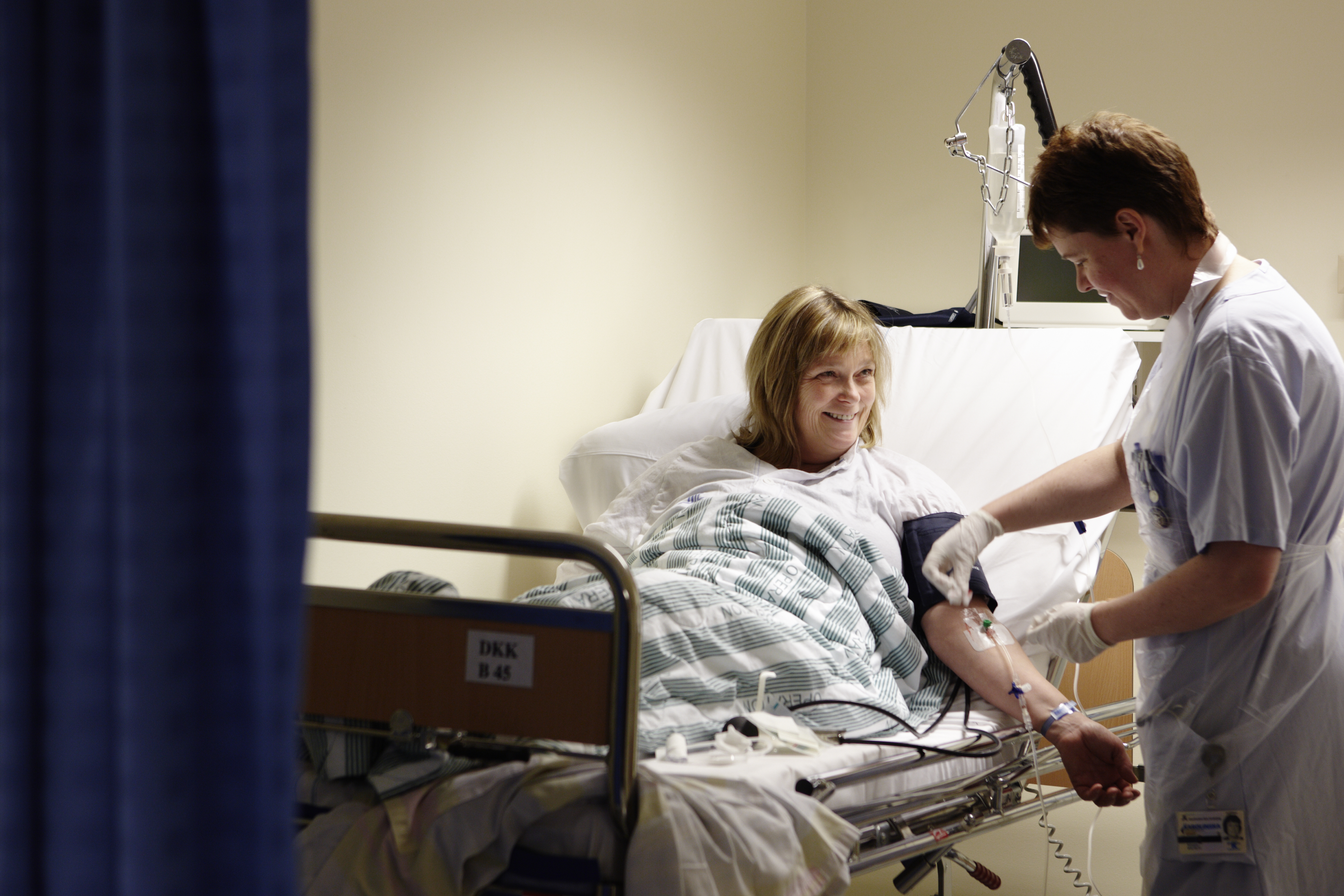 A patient, lying in a patient bed, and is being treated by health care professionals.