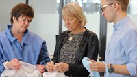 Tre personer tittar på operationsmössor Foto: Josefin Lundgren Gawell