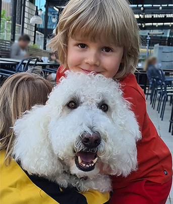 Glad sexårig pojke kramar vit hund