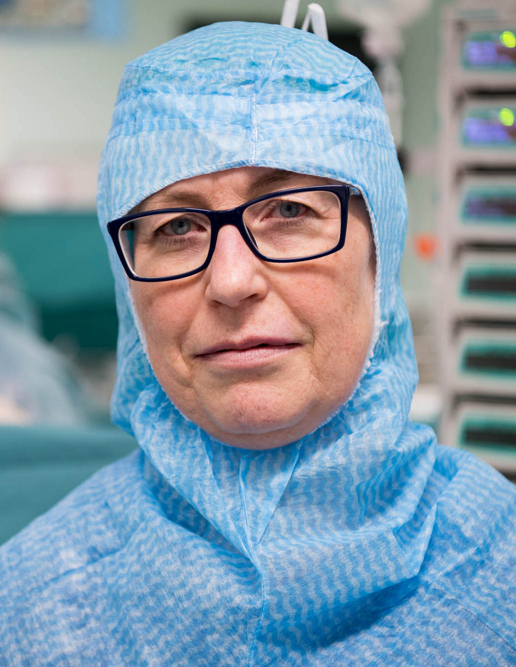bilden visar en kvinna i glasögon och blåvita operationskläder