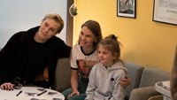 Sebastian och Nike håller om en liten flicka i soffan