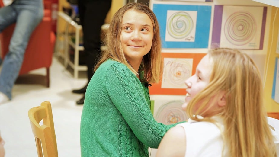 Greta Thunberg gör en pricktavla i ateljén tillsammans med en ung patient med blont lång hår.