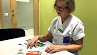 Anita sitter vid ett vit arbetsbord med utskrivna färgglada scheman framför sig.