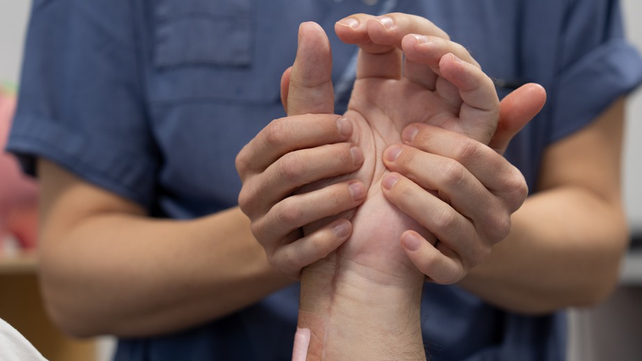 Den donerade handen hålls om av sjukhuspersonals händer.