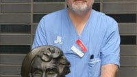vårdklädd man med staty