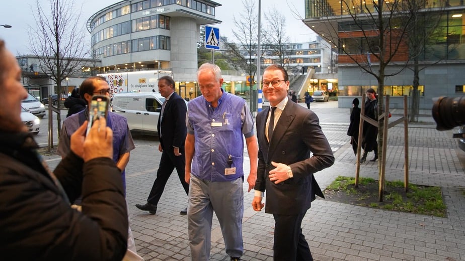 Två män kommer gående utanför ett sjukhus.