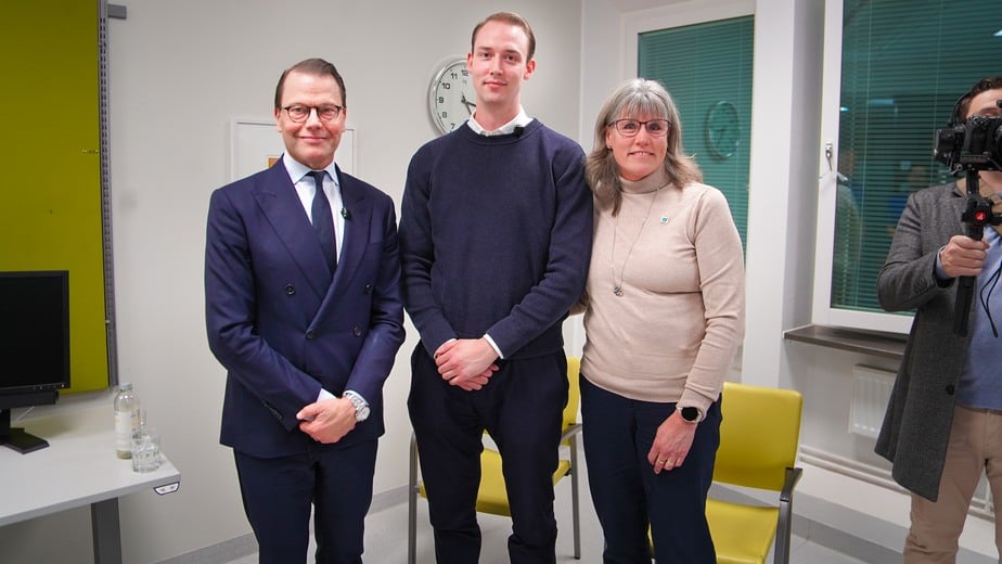 Två män och en kvinna står i ett gulvitt mottagningsrum.