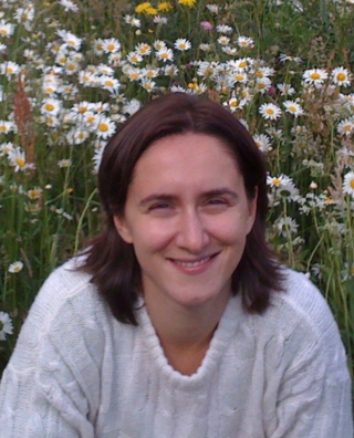 Privat bild på Amelia Chiorescu där hon sitter på en blommig sommaräng i vit stickad tröja.