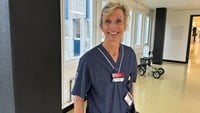 Blond läkare med håret uppsatt i en tofs och blå sjukhuskläder