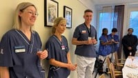 Vårdpersonal skålar i cider inne i ett konferensrum