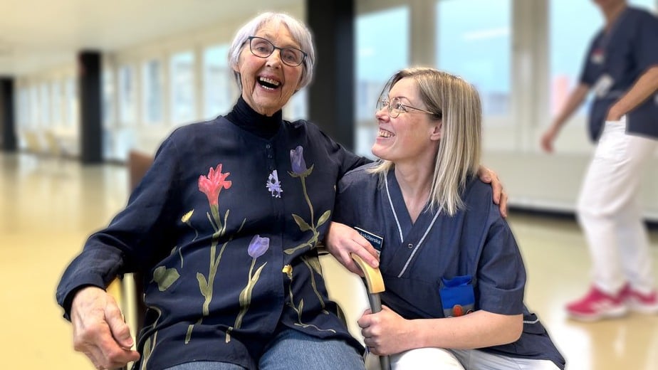 Ingrid sitter på en stol och sjuksköterskan Johanna sitter på huk intill.