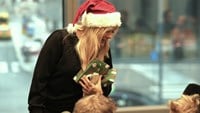 Pernilla Wahlgren delar ut julklappar till två pojkar.