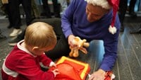 Martin Stenmarck leker på golvet med liten flicka i en röd julklänning.