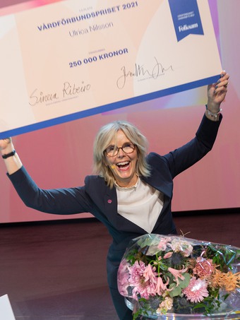 Ulrica Nilsson, vinnare av Vårdförbundspriset 2021 håller i en stor check på scen.