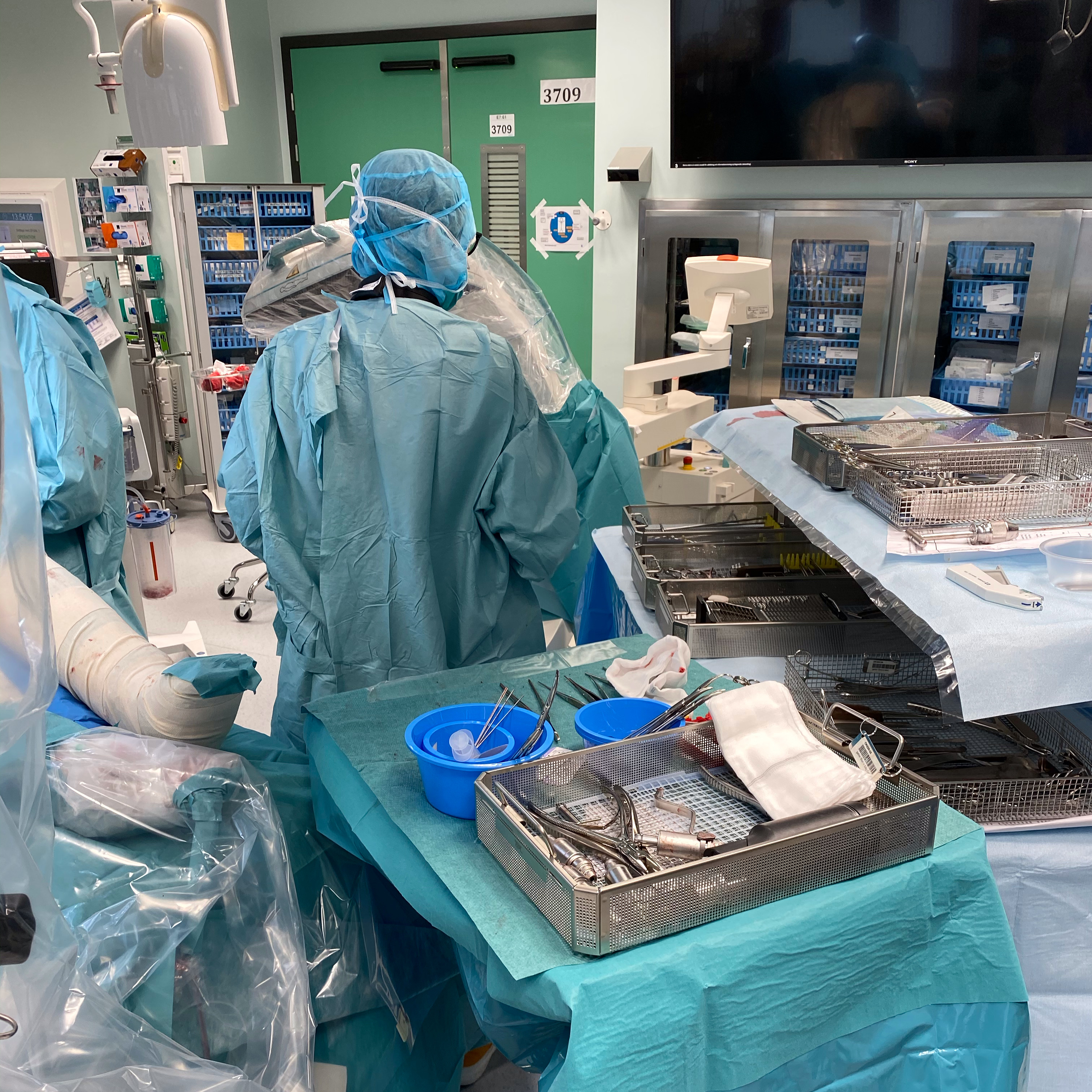sterilklädd kvinna som står bredvid operationsinstrument inne på operationssal