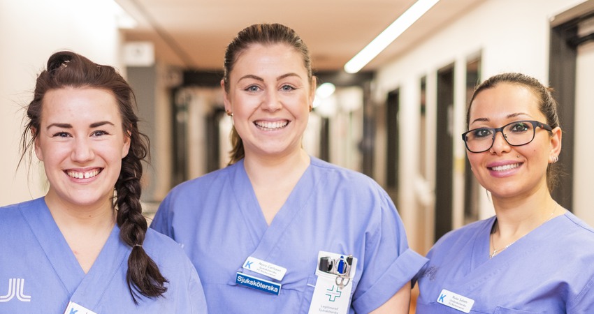 Gruppbild på vårdklädd sjuksköterska och undersköterska i korridor